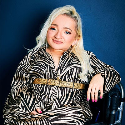 A photo of Samantha Renke smiling. She has long blonde hair and wears a zebra-print dress. 