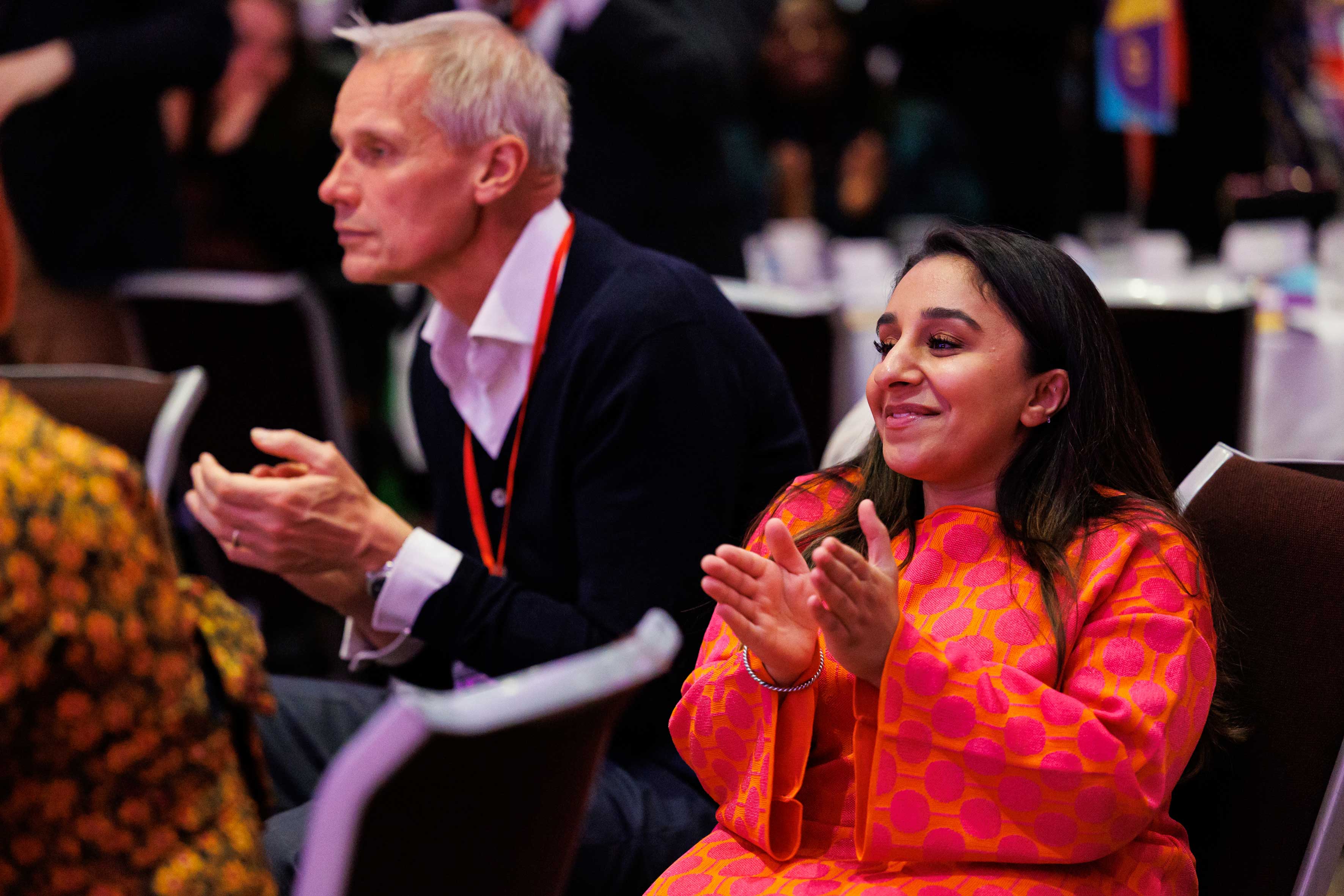 A woman in an orange dress and a man clapping