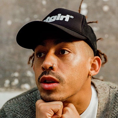 A photo of Jordan Stephens. He wears a black cap.