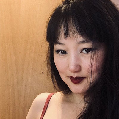 A photo of Lesta Woo. She has long, dark hair and wears dark lipstick.